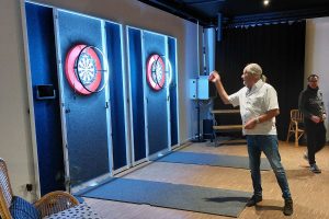 Dartspieler wirft auf beleuchtete Dartscheibe